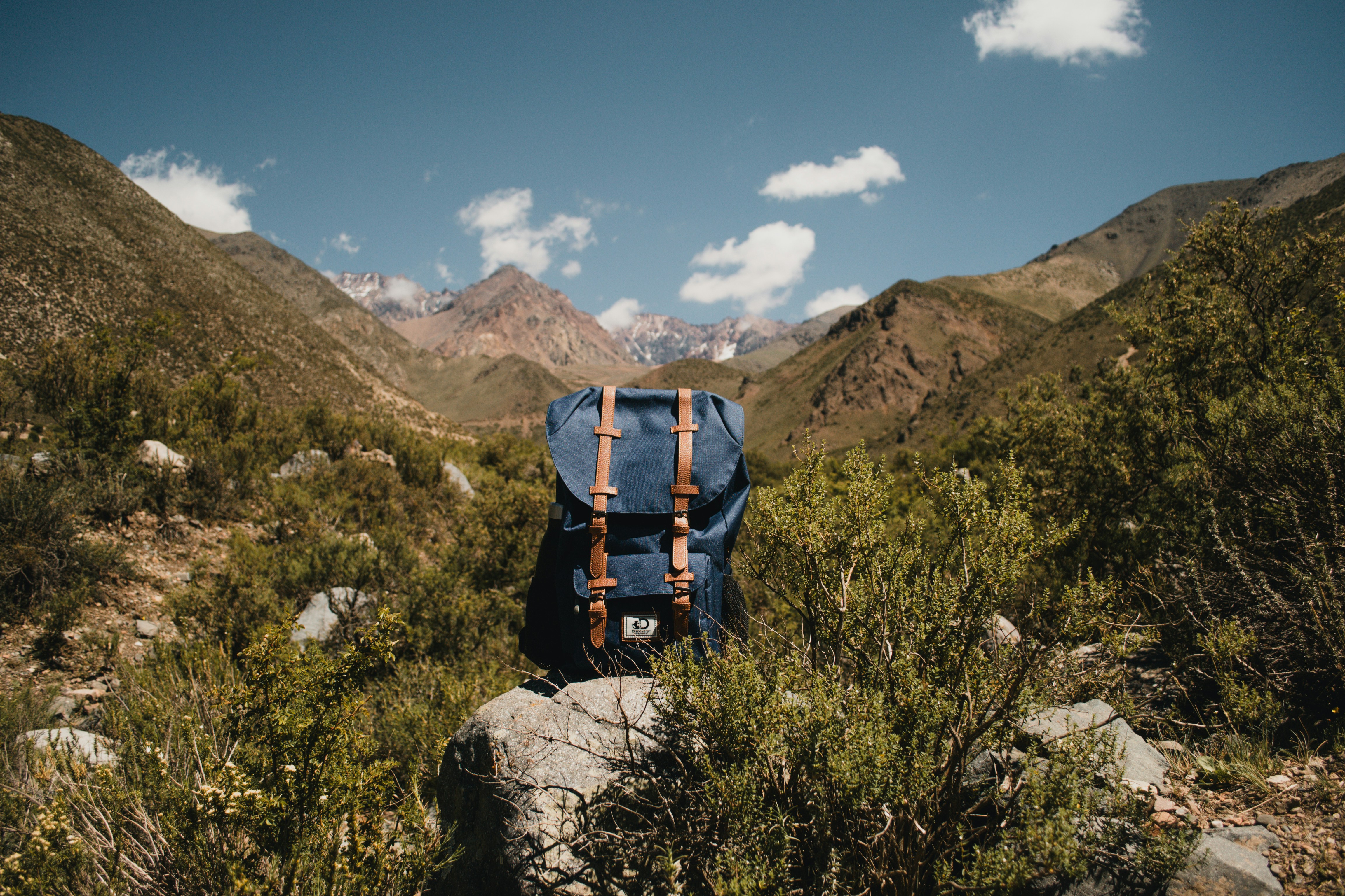 A backpack sitting on a mountain peak overlooking a vast valley, symbolizing independence.