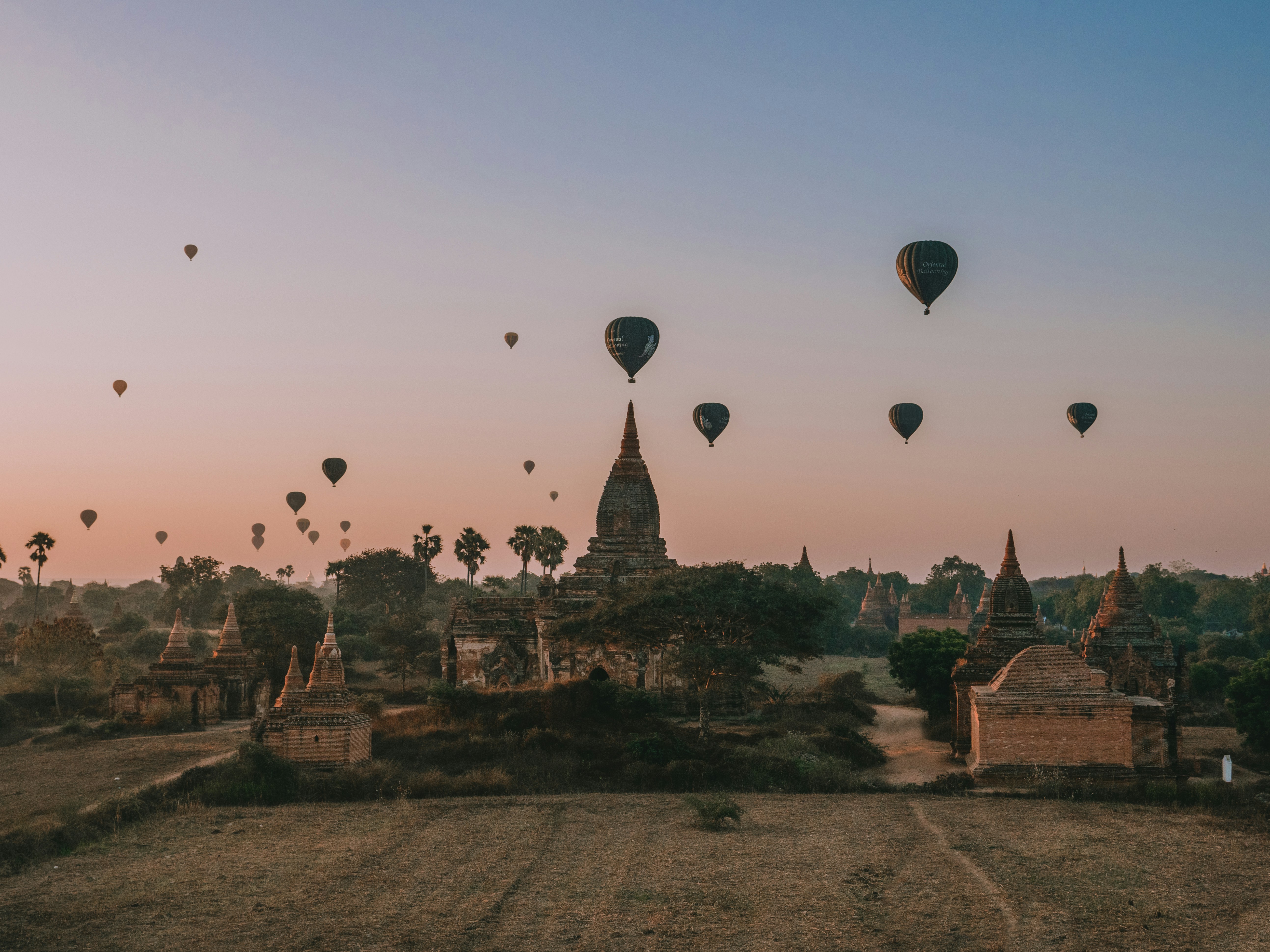 Silhueta de pagodes antigos com balões de ar quente coloridos a flutuar na luz dourada da manhã enevoada em Bagan