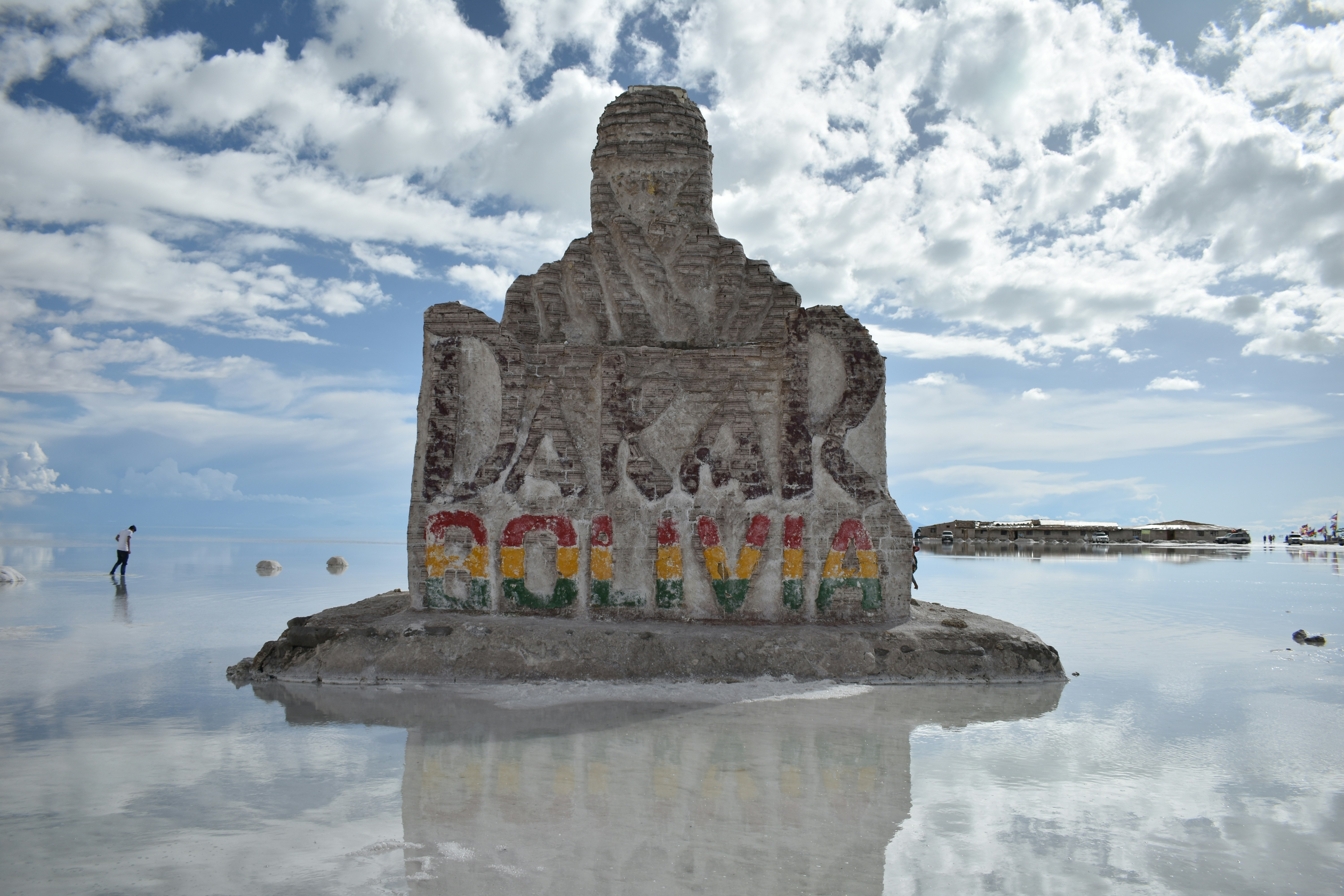 Um viajante de pé nas salinas refletivas de Uyuni durante um vibrante pôr do sol rosa e roxo
