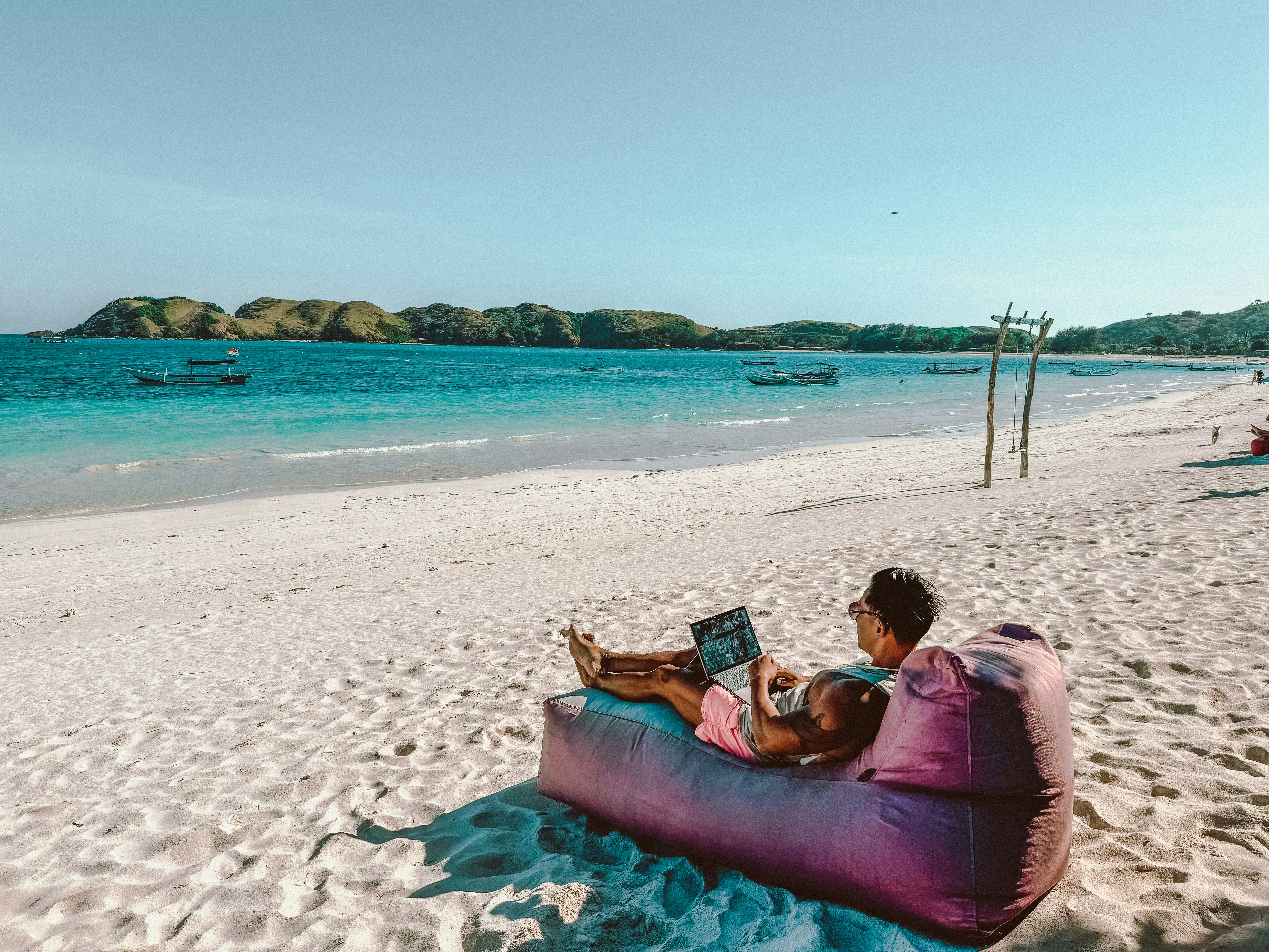 A person working on a laptop with a view of the turquoise Mediterranean sea.