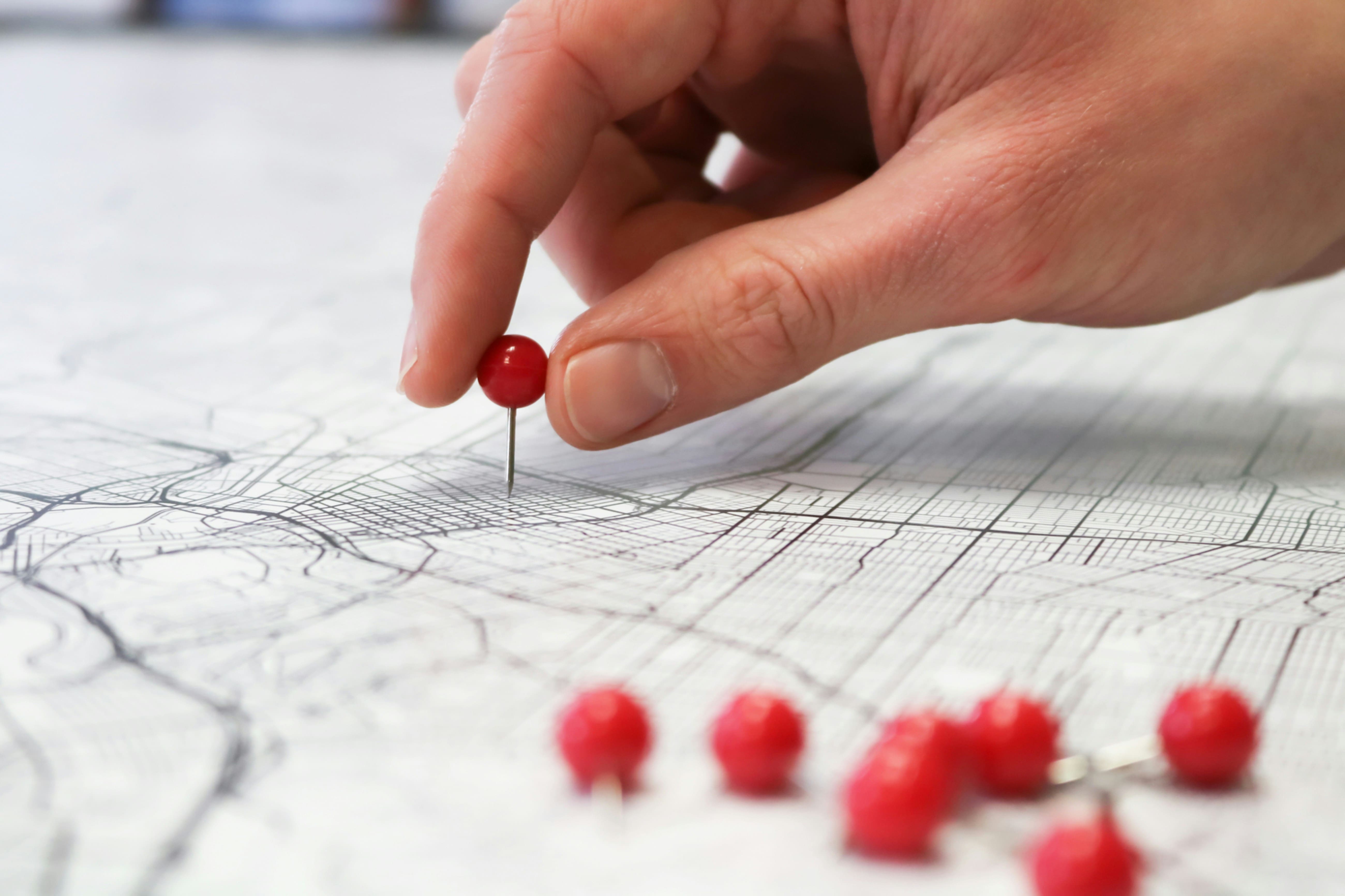 Uma mão a raspar um país num mapa mundo, revelando um destino colorido por baixo.
