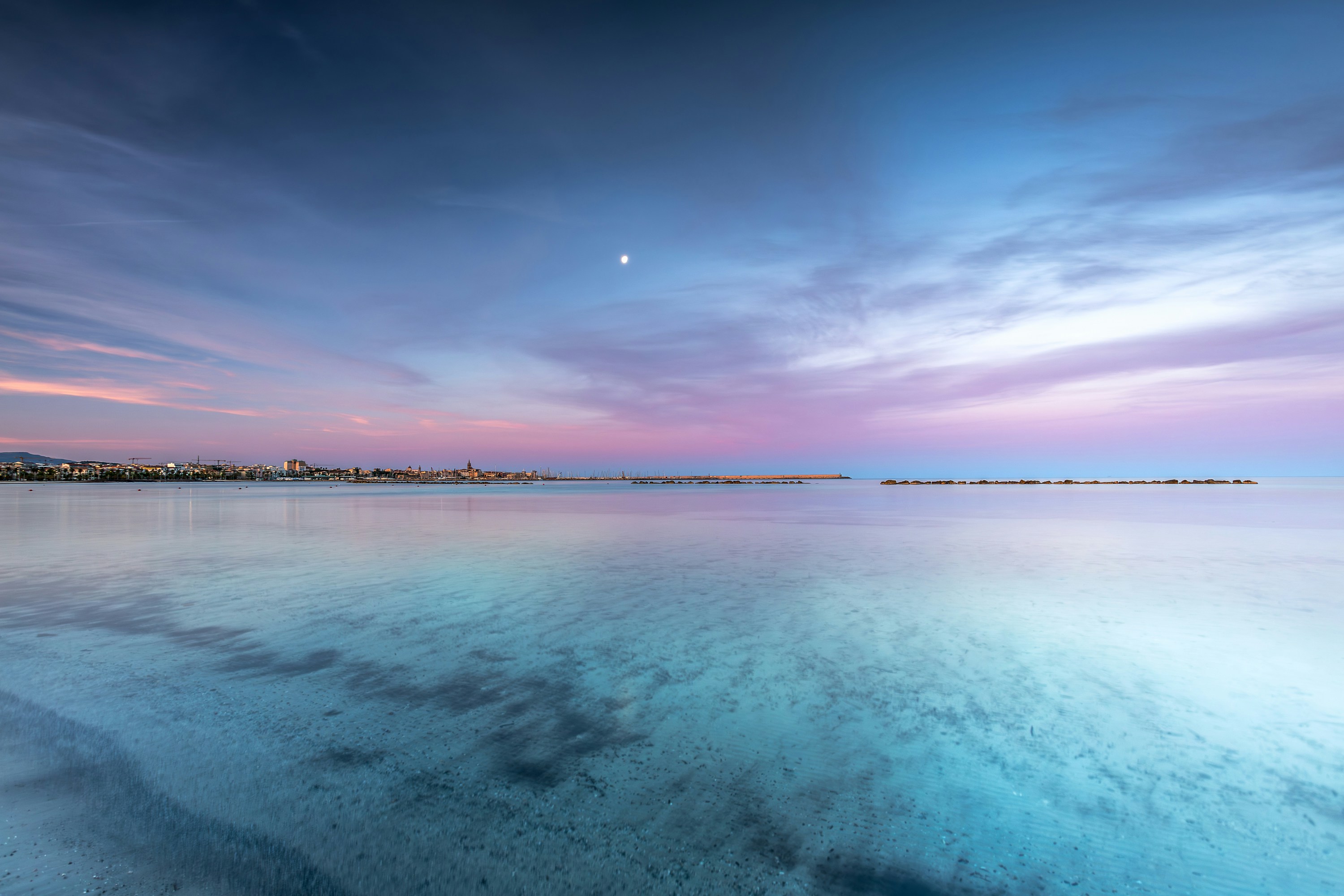 Uma colorida cidade costeira mediterrânea com água azul e sol forte de verão.