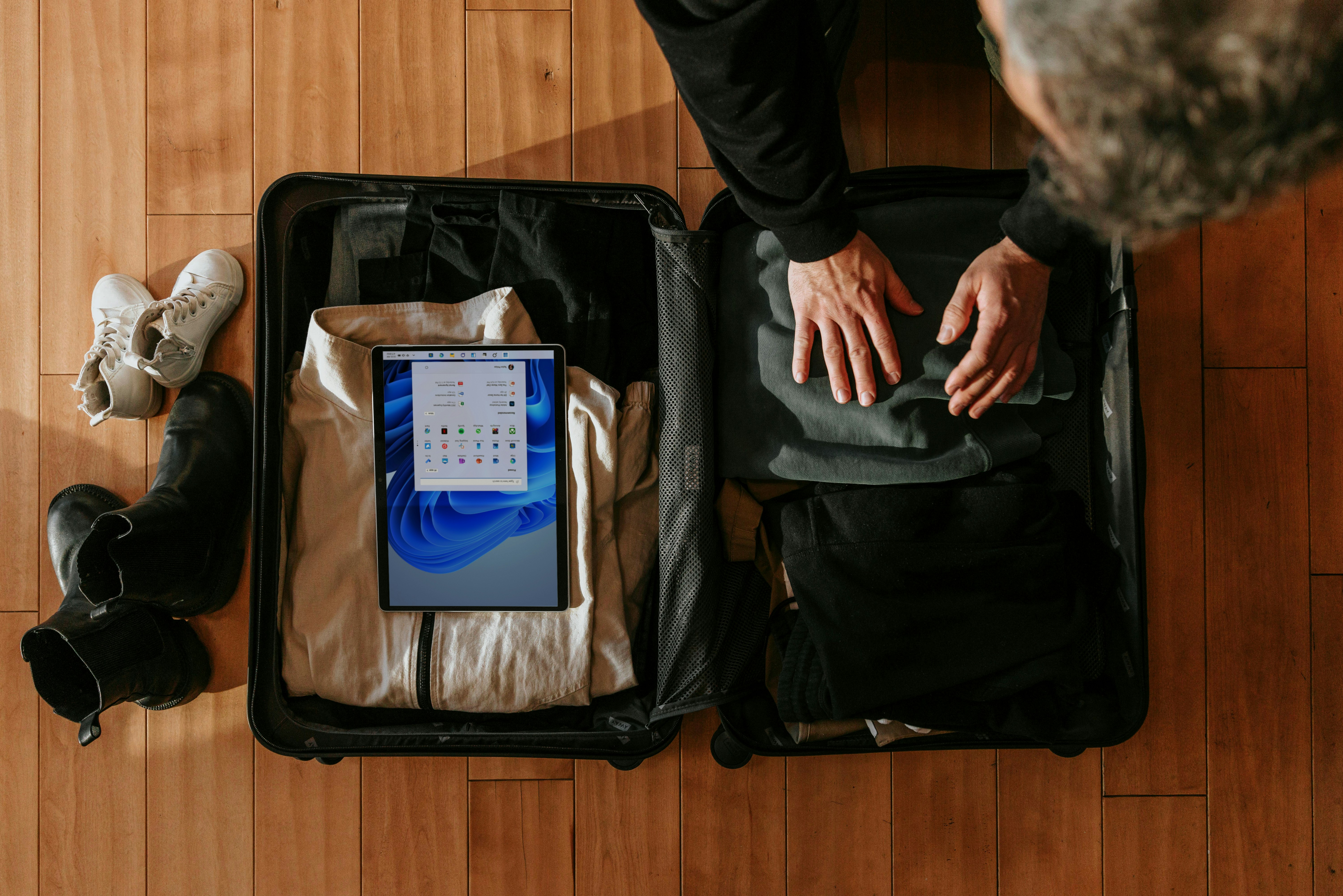 A traveler organizing packing cubes and travel gear on a bed