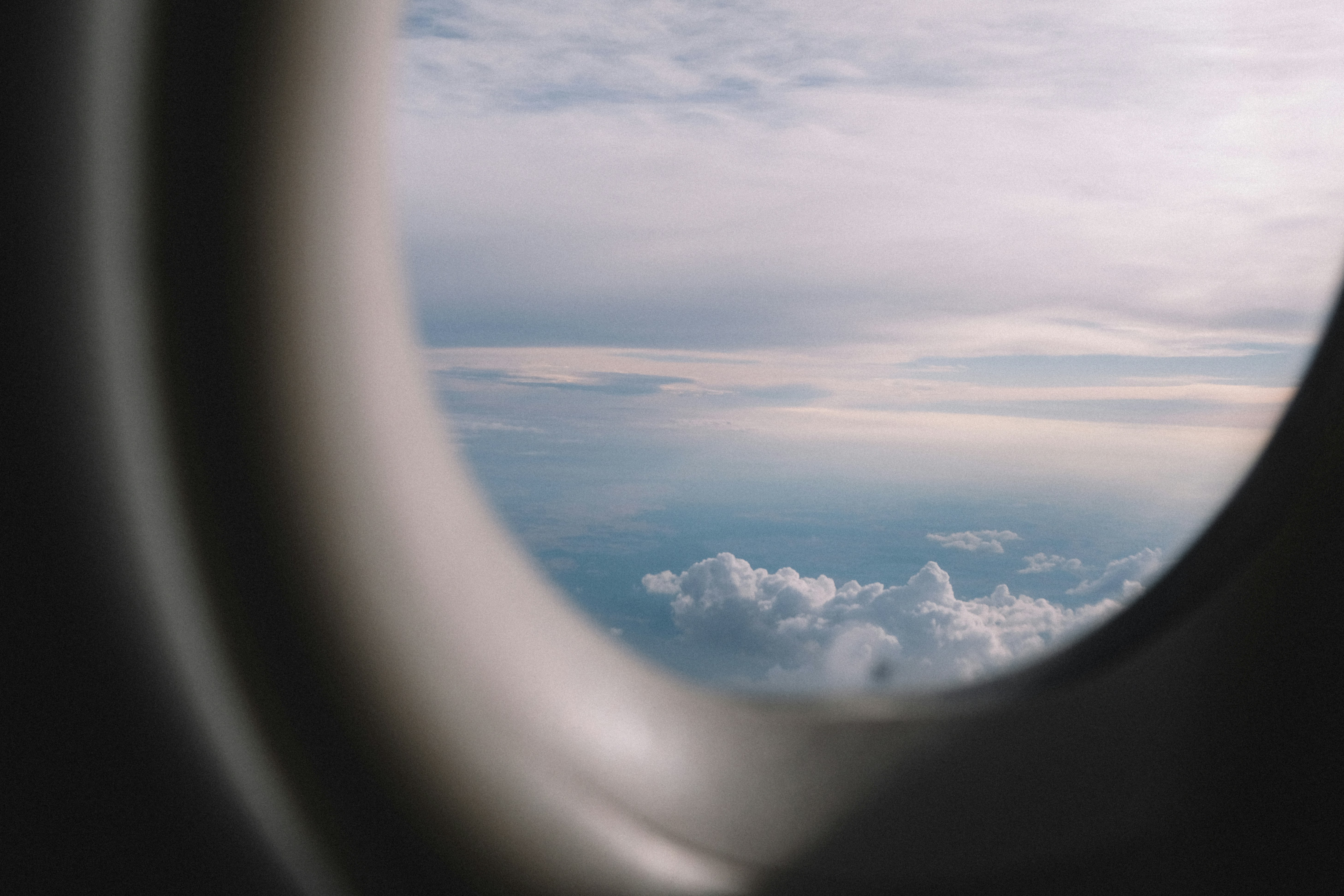 Vista da janela de um avião sobre nuvens brancas e fofas durante o pôr do sol.