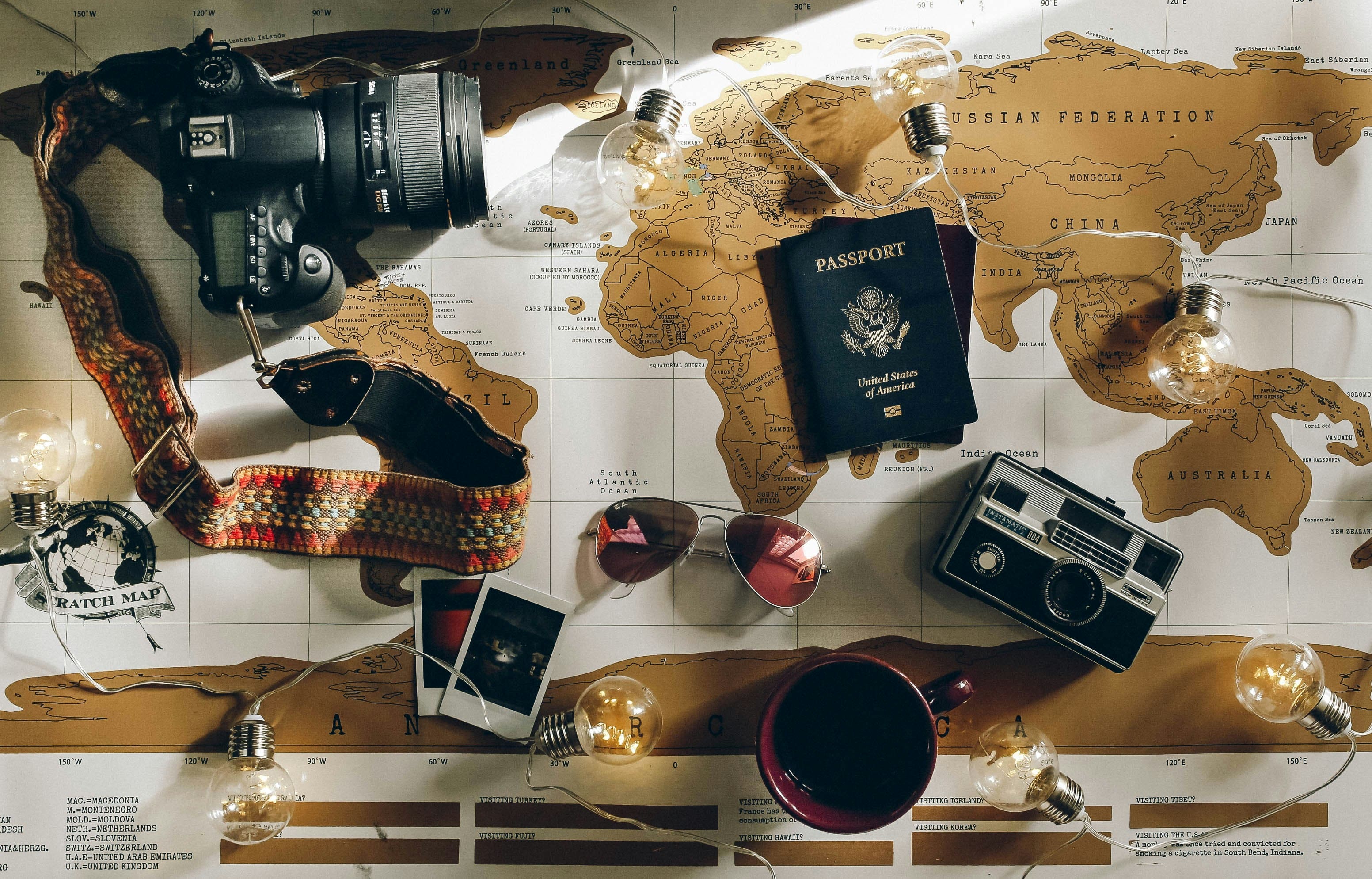 Viajante olhando para um laptop mostrando um mapa de viagens enquanto segura um mapa físico