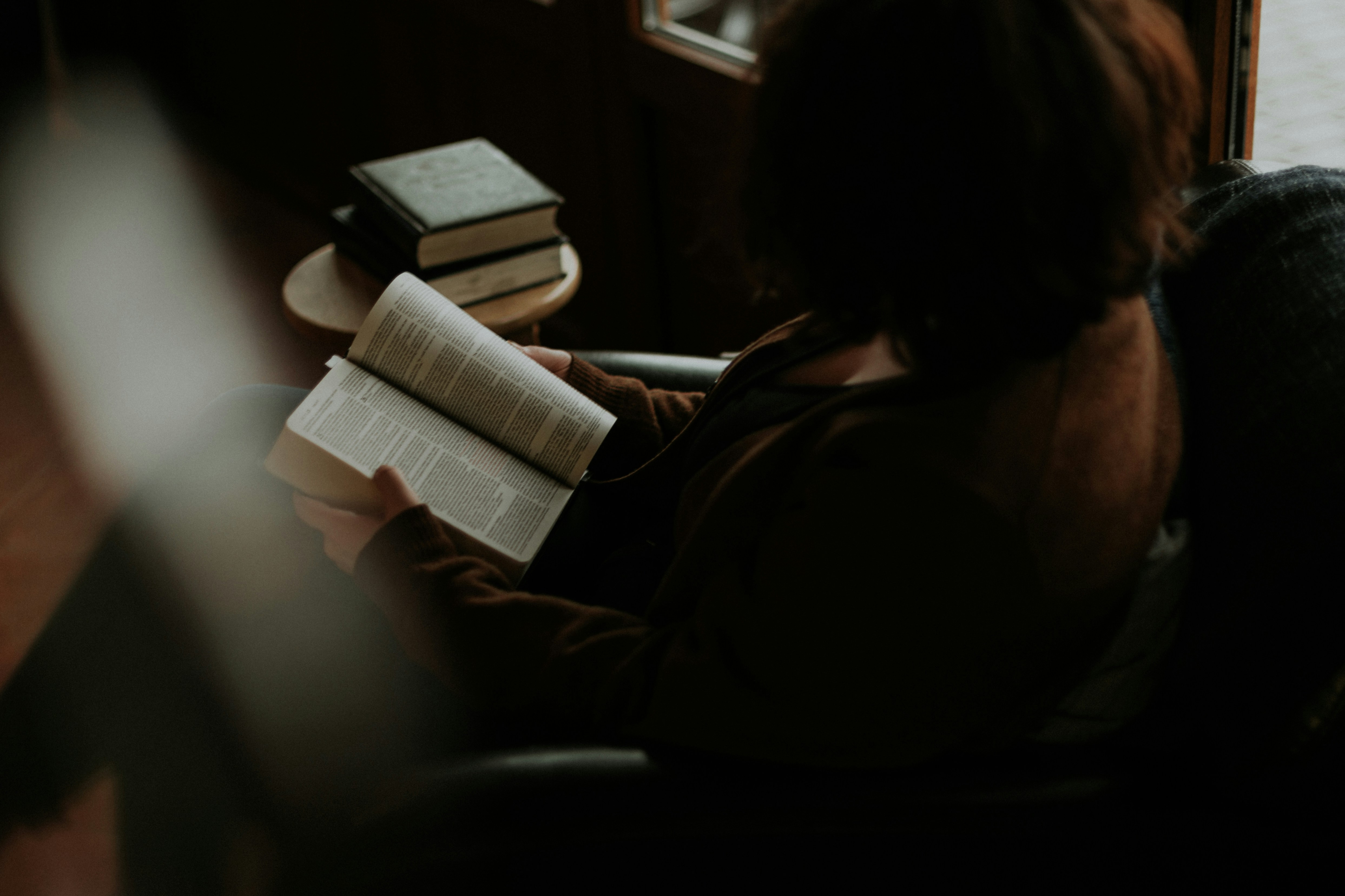 A young woman sitting at a cobblestone cafe in Europe, peacefully looking at her travel plans.
